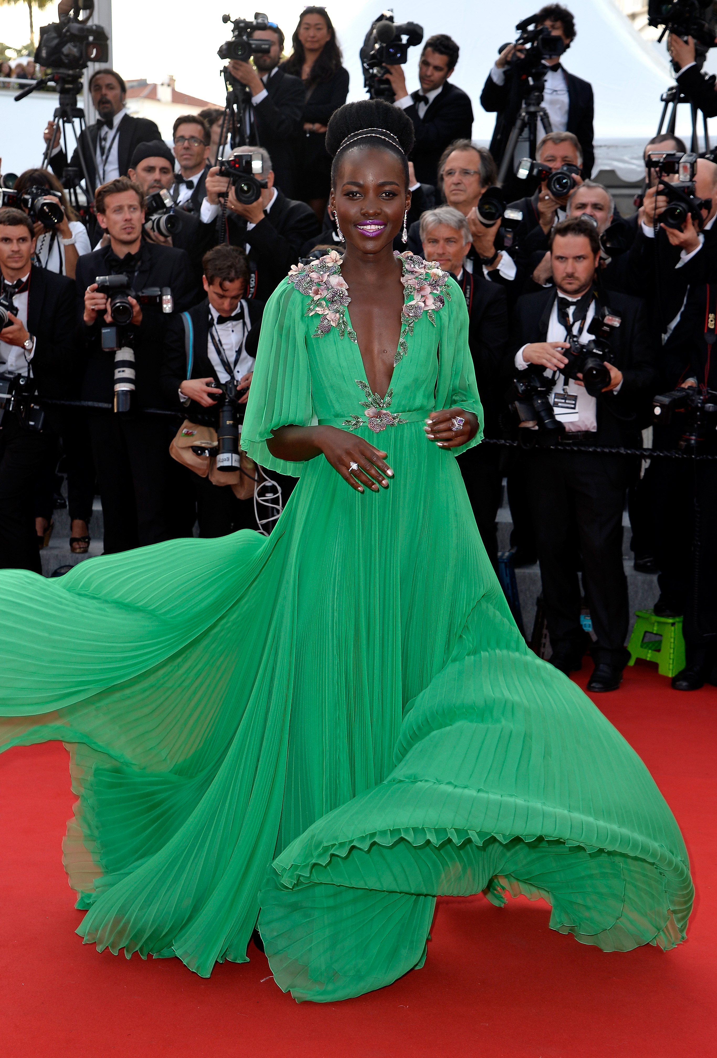 Lupita Nyong'o usando vestido verde longo com apliações florais