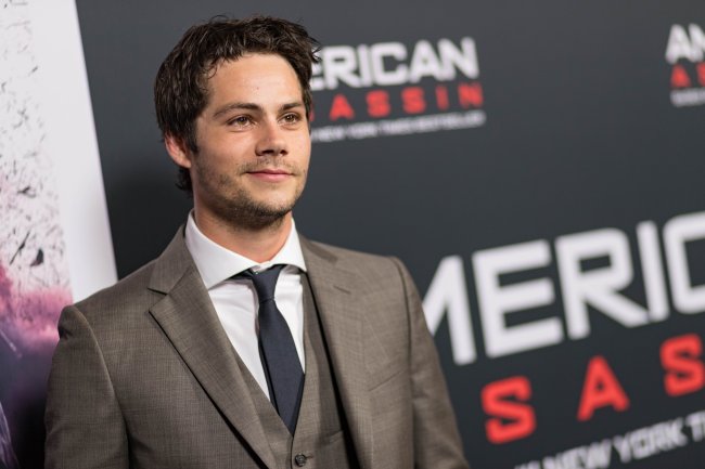 Screening Of CBS Films And Lionsgate’s “American Assassin” – Red Carpet Dylan O'Brien posando para foto em carpet de evento com terno marrom, camisa branca e gravata preta; o ator sorri levemente