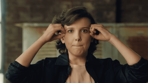 millie bobby brown gif Gif da Millie Bobby Brown com as duas mãos ao lado da cabeça fazendo gesto de explosão e expressão facial surpresa