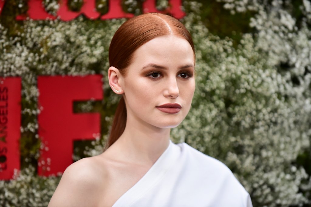 Madelaine Petsch em um evento da InStyle com o cabeo preso em rabo de cabalo baixo, batom vermelho e roupa branca