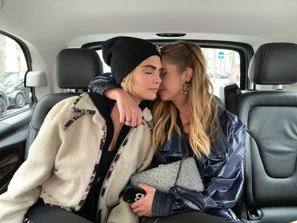 Ashley Benson e Cara Delevingne no carro abraçadas; a atriz está com o rosto escondido no pescoço de Cara e o braço em volta da modelo que tem os olhos fechados