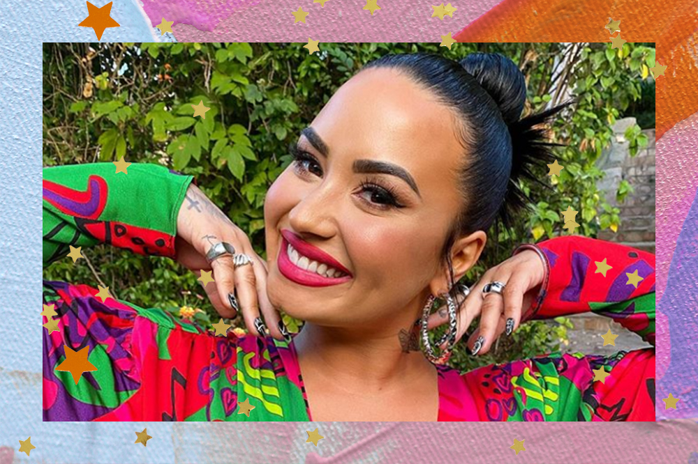 Demi Lovato sorrindo com as mãos levantadas perto do rosto