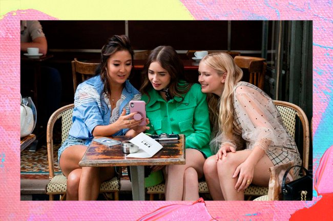 Mindy, Emily e Camille, sentadas diante de uma mesa quadrada. Todas elas estão olhando curiosas para um celular