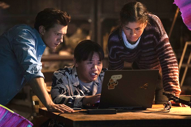 homem-aranha 3 Três garotos olham curiosos para a tela de um computador. Um deles está sentado e os outros dois em pé, um em cada lateral