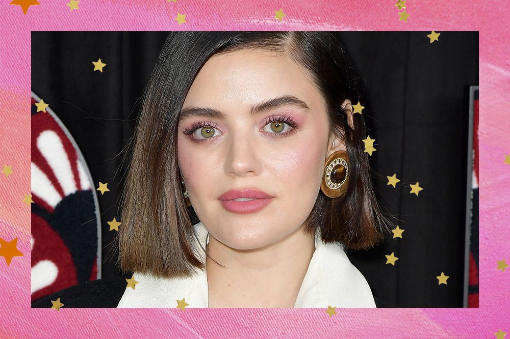 Lucy Hale posando para foto com expressão séria, ela usa o cabelo solto e uma maquiagem com sombra em tons de rosa