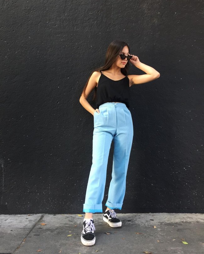 Olivia Rodrigo usando blusa regata preta, calça azul e tênis preto