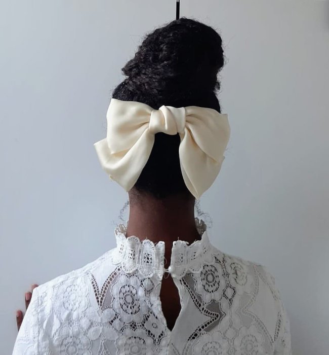 garota de costas com o cabelo preso em um coque amarrado com um laço branco