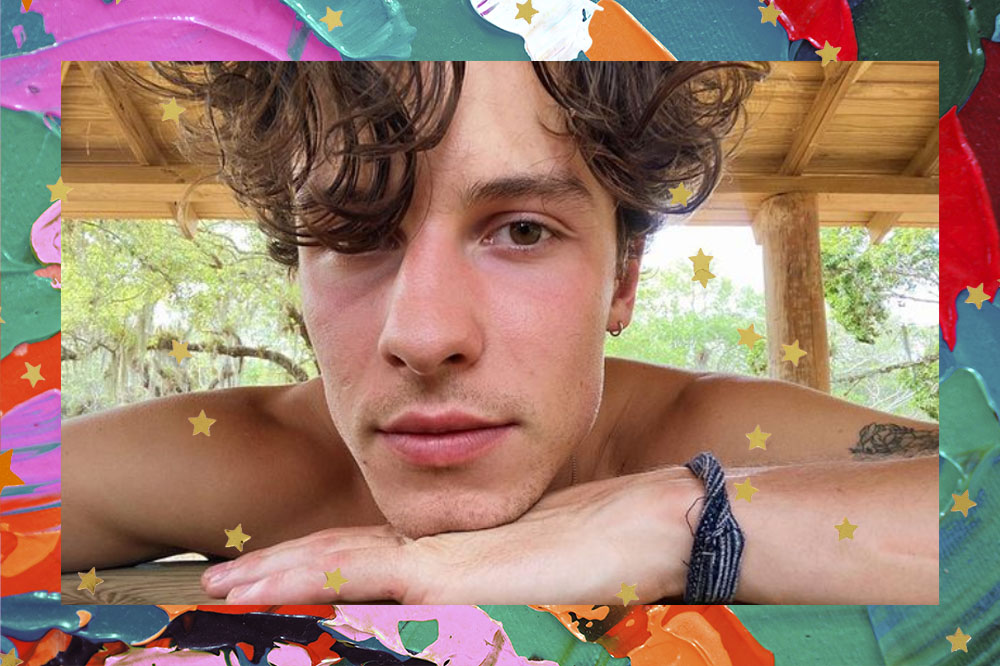 shawn-mendes-hashtag Shawn Mendes olhando para a câmera e com o rosto apoiado em uma das mãos