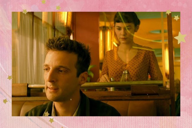 amelie10 Amélie olha para Nino através e um vidro do café em que trabalha. Ela está em pé e ele sentado em uma das mesas