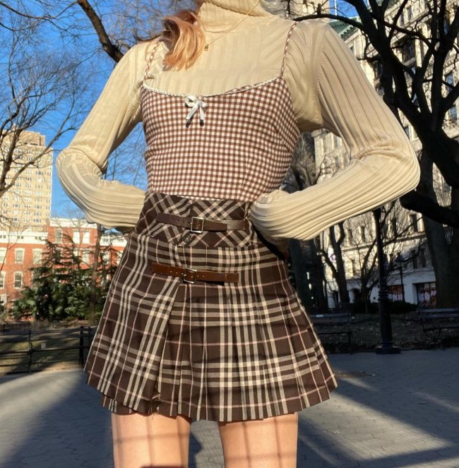 Inspiração de look com saia xadrez Sobreposição de blusa bege com gola role, e regata com alça fina xadrez e saia xadrez marrom.