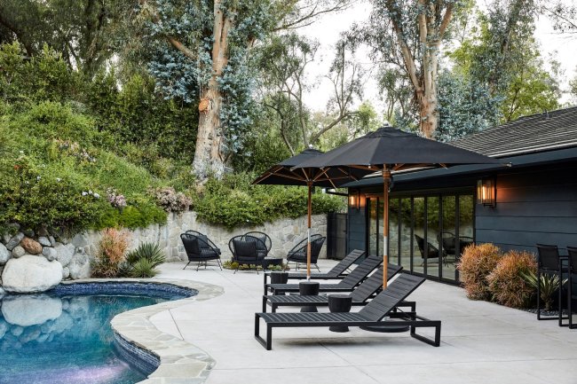 miley1 Área externa da casa de Miley Cyrus. Na imagem aparece três cadeiras pretas com guarda-sóis em primeiro plano, a piscina e ao fundo mais cadeiras pretas