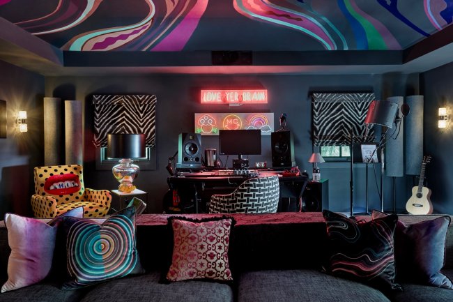 miley6 Estúdio na casa de Miley Cyrus. A imagem mostra um sofá com almofadas, letreiros luminosos na parede, quadros com estampa animal print e uma pintura no teto