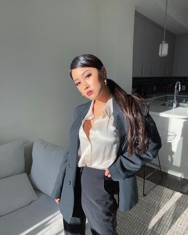 Heyoon, do Now United, posando com camisa branca semi aberta, calça social escura e blazer.