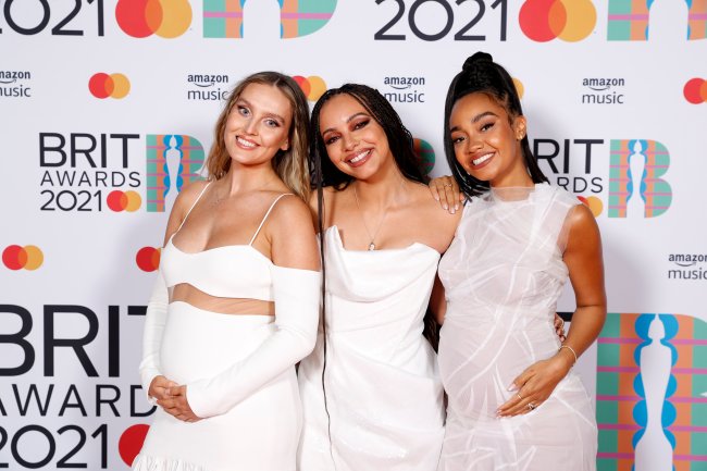 The BRIT Awards 2021 – Media Room Perrie Edwards, Jade Thirlwall e Leigh-Anne Pinnock, do Little Mix, no BRIT Awards 2021. Perrie, à esquerda, está sorrindo, usando um vestido longo branco com uma transparência entre a parte de cima e a saia, e as duas mãos na sua barriga de grávida. Jade, ao meio, está com um vestido branco sem alças e sorrindo. Leigh-Anne, à direita, está com um vestido branco levemente transparente, sorrindo, e as duas mãos na sua barriga de grávida.