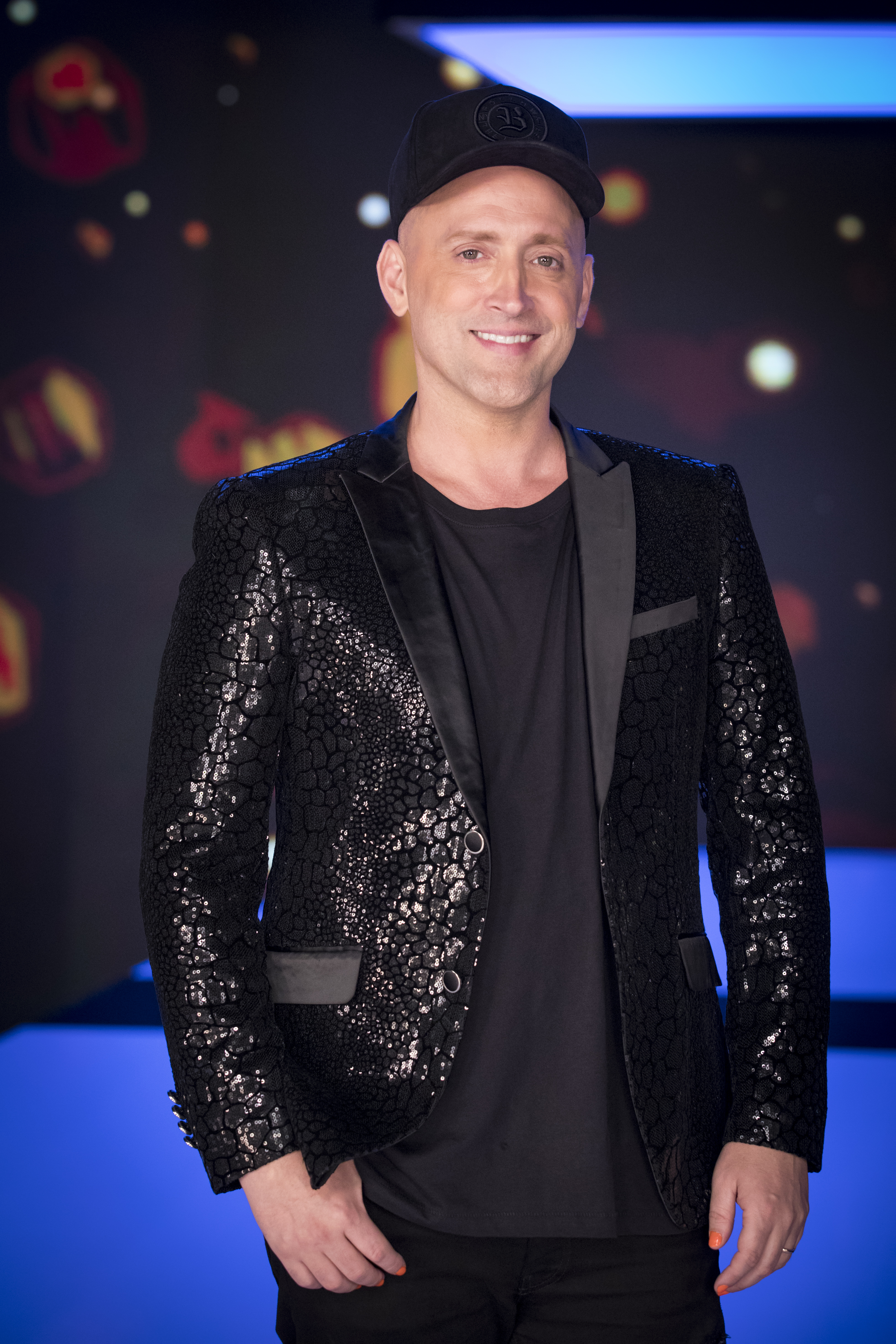 Institucional Paulo Gustavo sorrindo enquanto posa para foto vestindo roupas pretas e boné