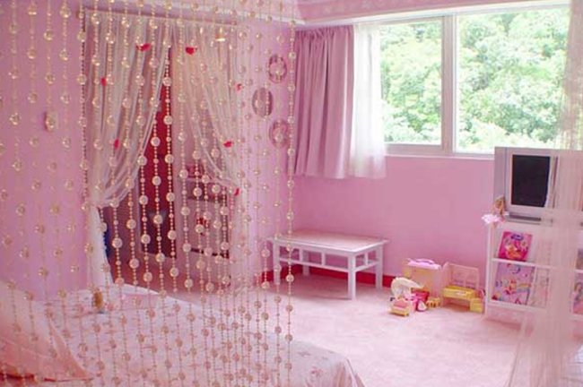 8 invenções que você fez no quarto, mas se arrependeu totalmente depois Quarto teen todo rosa com uma cortininha de miçangas ao lado da cama