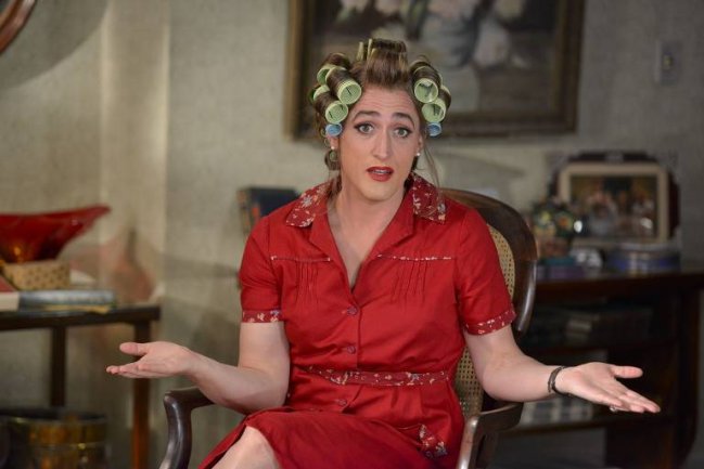 mae3 Dona Hermínia, personagem interpretado pelo ator Paulo Gustavo, de vestido vermelho, batom vermelho e bobs de cabelo.