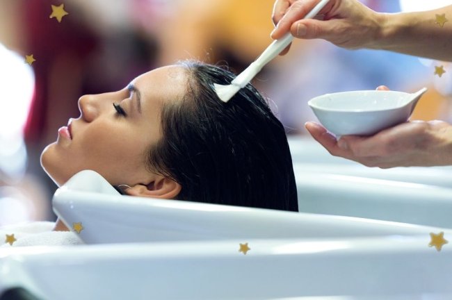 argila branca no cabelo Na imagem podemos ver uma cabeça apoiada em um lavatório branco de salão de cabeleireiro enquanto aplicam algum produto branco com a ajuda de um pincel.