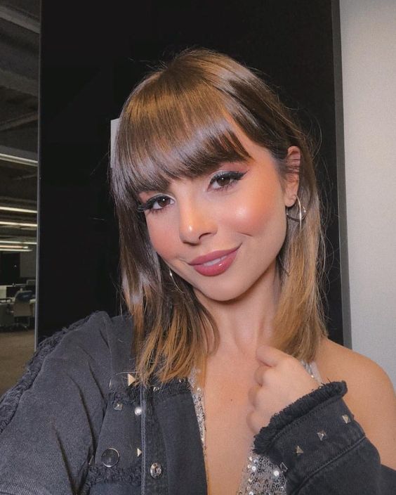 Selfie da blogueira Giovanna Ferrarezi. Ela usa uma jaqueta preta, cabelo solto e franja reta. Ela olha para a câmera e sorri.