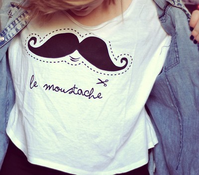 Foto de uma menina usando uma camiseta branca com estampa de bigode.