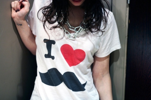 camiseta-estampa-bigode Foto da camiseta branca com estampa de bigode em uma mulher.