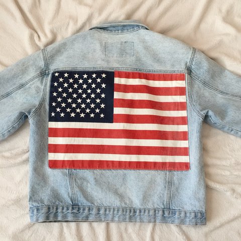 jaqueta-bandeira-eua Foto de uma jaqueta jeans com a estampa da bandeira dos Estados Unidos nas costas.