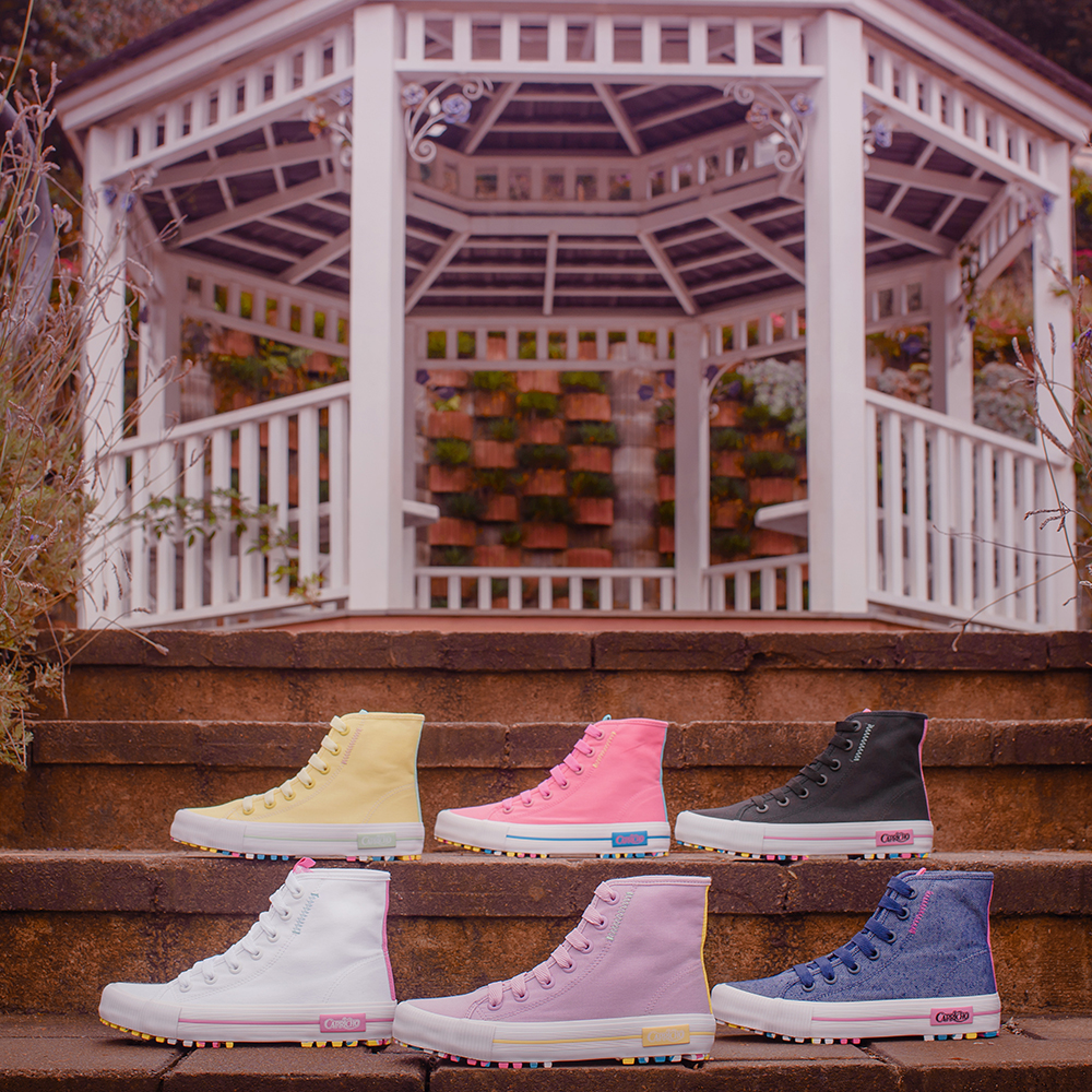 nova-colecao-tenis-capricho-shoes-01 Foto com seis tênis de cano alto da coleção da CAPRICHO Shoes em uma escada com um gazebo branco ao fundo. No degrau de cima, estão os tênis amarelo, rosa e preto e, no de baixo, os tênis branco, lilás e jeans.