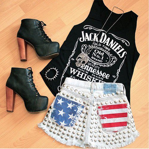 short-bandeira-eua Foto de um look com regata preta com estampa Jack Daniels, short com estampa da bandeira dos Estados Unidos e sapato LITA.