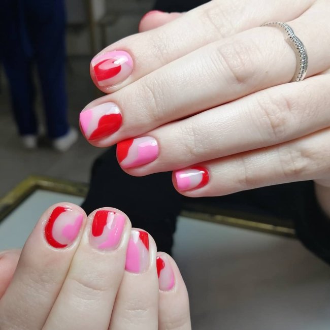 unha com vermelho e rosa Foto com foco nas mãos mostrando nail art rosa com detalhes vermelhos.