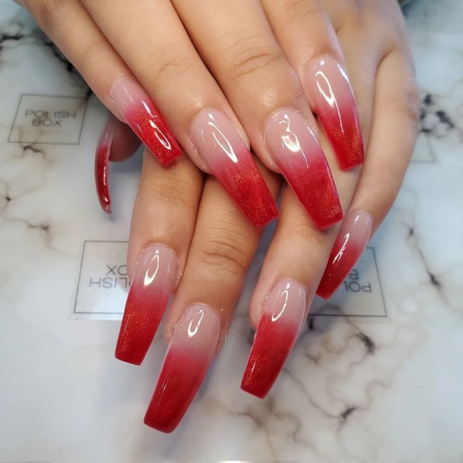 Foto com foco nas mãos exibindo a nail art das unhas. No caso, unhas vermelhas com degrade de cor