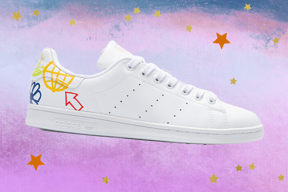 adidas-stan-smith-tenis-classicos Montagem do tênis Adidas Stan Smith branco em fundo degradê de lilás e azul com estrelas douradas e laranjas