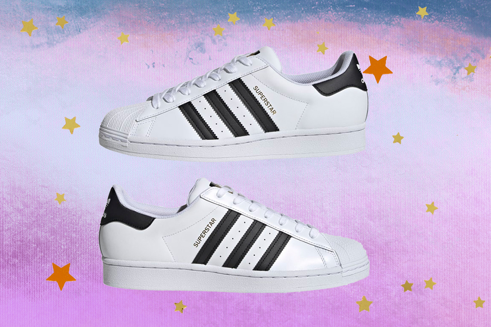 Montagem do tênis Adidas Superstar preto e branco em fundo degradê de lilás e azul com estrelas douradas e laranjas