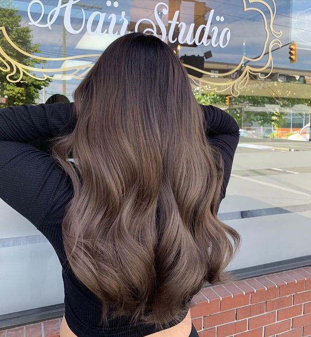 cabelo-castanho-acinzentado Foto de uma mulher de costas mostrando o cabelo. Ela usa uma blusa de manga longa preta e mostra o cabelo longo castanho acinzentado.