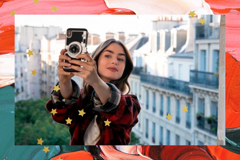 Personagem Emily segurando um celular e fazendo uma selfie. Ao fundo, aparece a cidade de Paris.