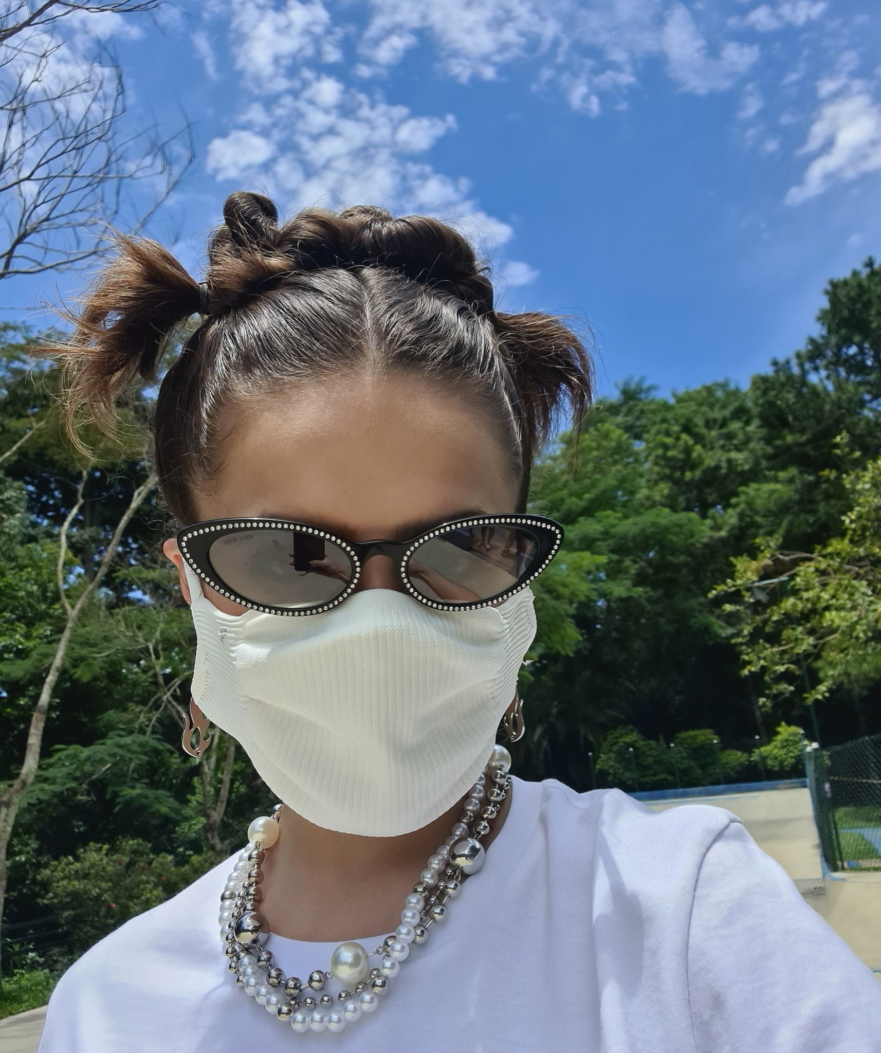 Maisa Silva usando óculos de sol e colar de pérolas, camiseta branca e máscara de proteção branca