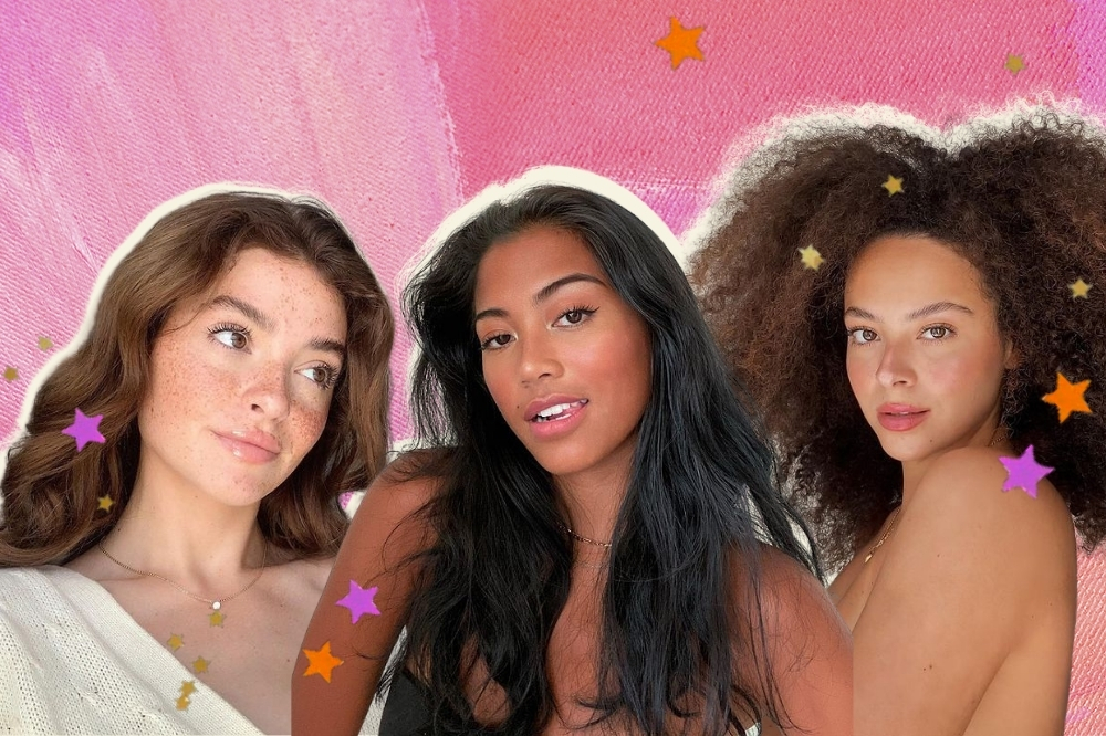 Montagem com o fundo rosa e detalhe de estrelas coloridas com a foto de três meninas. A garota da esquerda usa um cardigan branco, colarzinho dourado, cabelo castanho acobreado solto e maquiagem natural com gloss. Ela olha para o lado e sorri levemente. A garota do meio usa um top cropped preto, colarzinho dourado, está com o cabelo solto e maquiagem natural. Ela olha para a câmera e sorri levemente. E a garota da direita usa um top branco, cabelo crespo castanho iluminado solto e maquiagem natural. Ela olha para a câmera e não sorri.