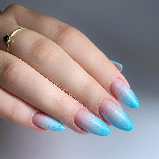 unha-baby-boomer-azul Foto de uma mão com foco nas unhas decoradas no estilo baby boomer em um tom de azul.