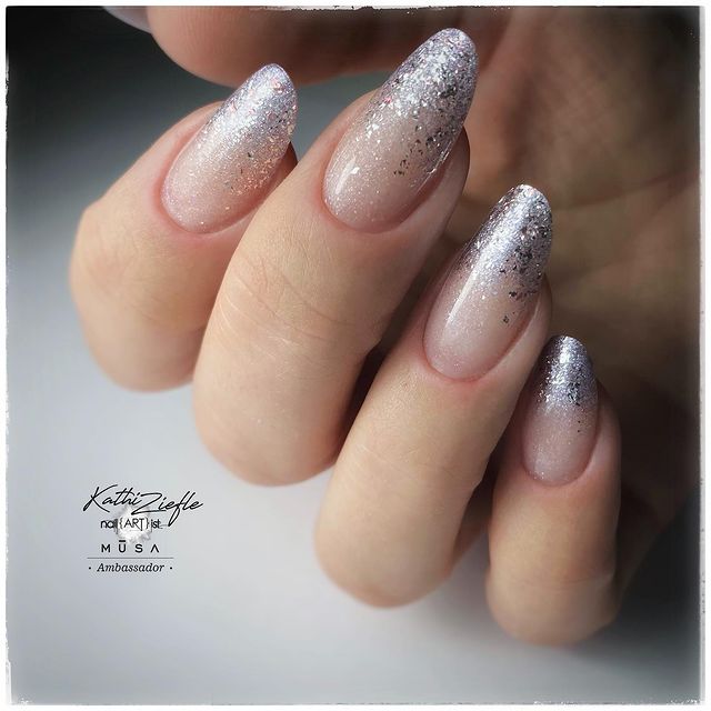 unha-baby-boomer-glitter Foto de uma mão com foco nas unhas decoradas no estilo baby boomer com um glitter prata.