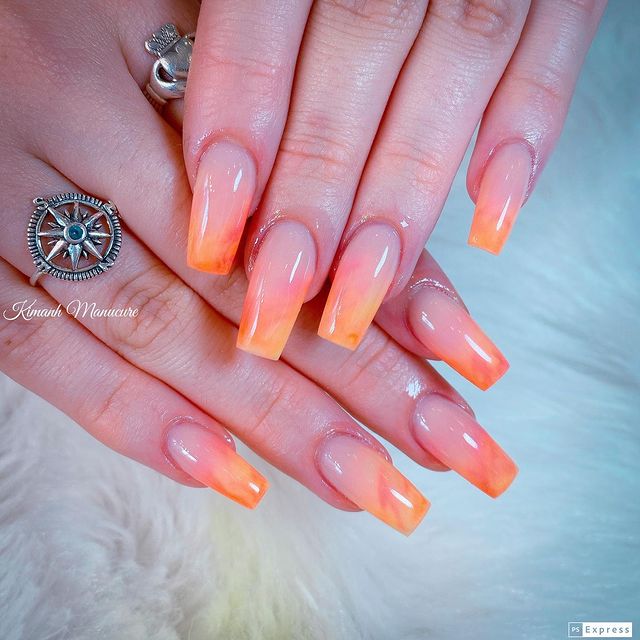 unha-baby-boomer-laranja Foto de duas mãos com close nas unhas decoradas no estilo baby boomer em um tom de laranja.