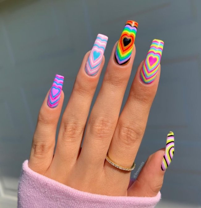 Foto com foco nas unhas exibindo a nail art chamada bubble heart, que traz vários corações um dentro do outro.