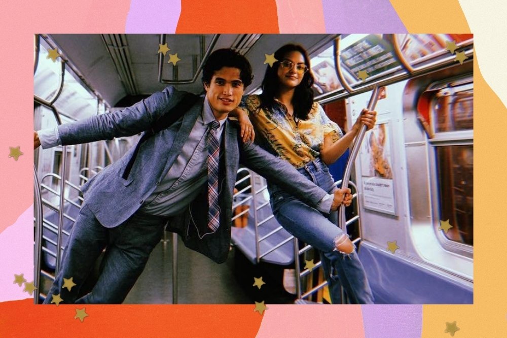 Charles Melton e Camila Mendes posando dentro do vagão de um trem. Ele usa terno e ela blusa amarela com calça jeans.