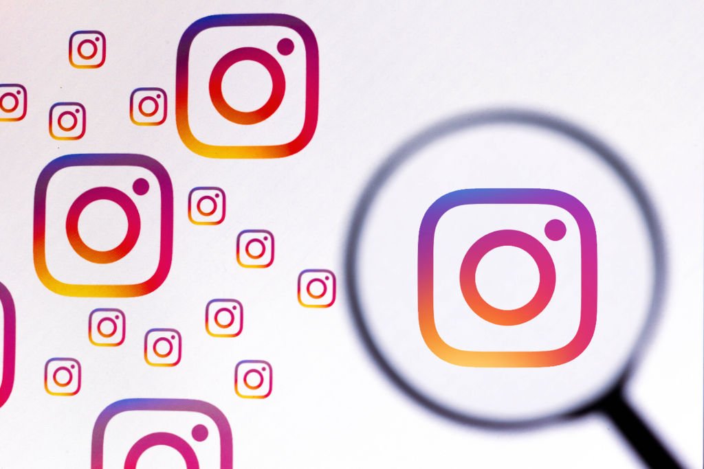 Arte com vários logos do Instagram espalhados sobre um fundo branco. Em um deles, há uma lupa sobreposta
