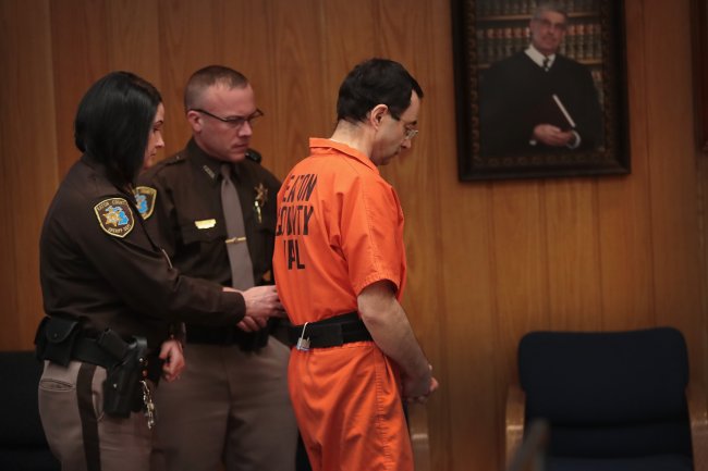 Larry Nassar no tribunal, sendo escoltado por policiais, após ser condenado a até 175 anos de prisão por crimes de assédio sexual