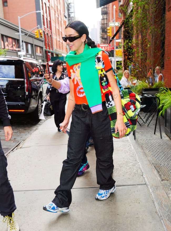 Cantora Dua Lipa andando pelas ruas de NY com blusa colorida e cachecol verde.