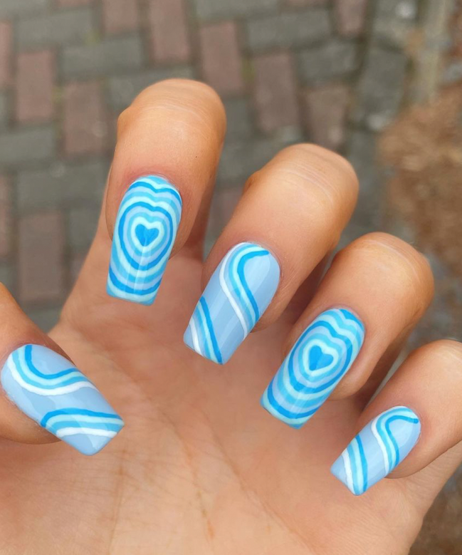 bubble heart azul Foto com foco nas unhas exibindo a nail art chamada bubble heart, que traz vários corações um dentro do outro.
