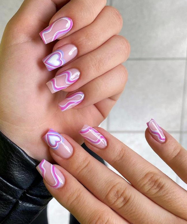 Foto com foco nas unhas exibindo a nail art chamada bubble heart, que traz vários corações um dentro do outro.