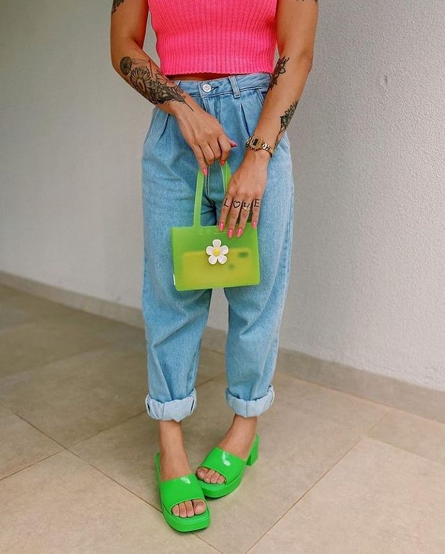 look-com-tamanco-verde Foto do look de uma mulher. Ela usa uma blusa rosa, calça mom jeans, bolsa verde e tamanco verde. A foto não mostra o rosto dela.