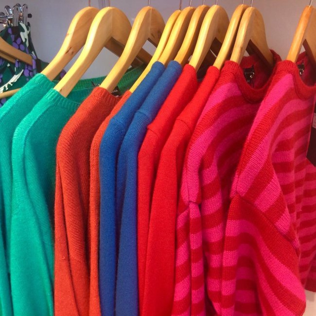 roupas coloridas Arara com blusas coloridas penduradas, nas cores verde, azul, vermelho e rosa.