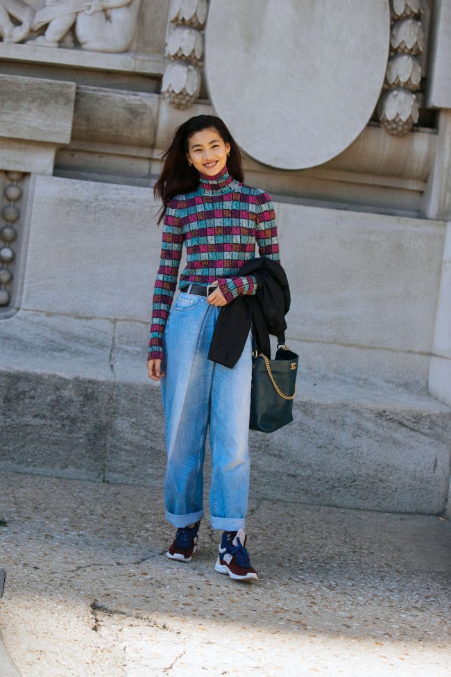Jung Ho-yeon Jung Ho-yeon com calça jeans e tênis posando sorridente.
