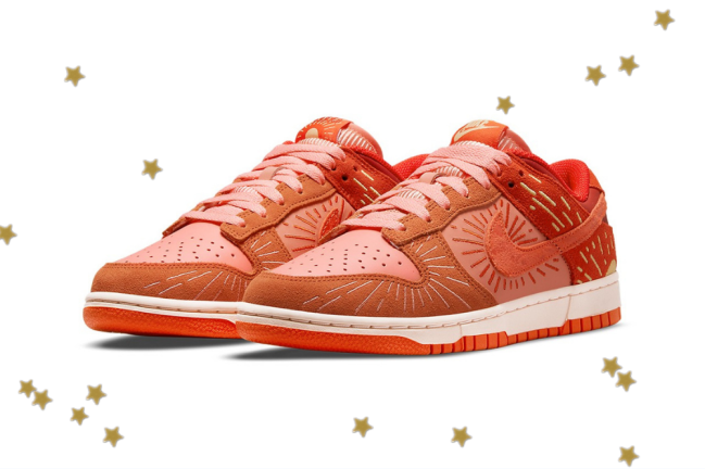 Dunk low nike Foto com fundo branco e com estrelinhas douradas. No centro, temos o novo tênis da Nike do modelo Dunk Low com as cores laranja, vermelho e detalhes em amarelo.